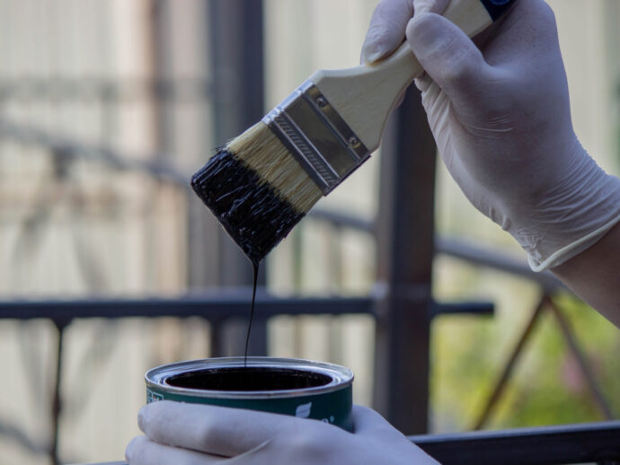 close-up of a hand painting a metal pipe. Selective focus.